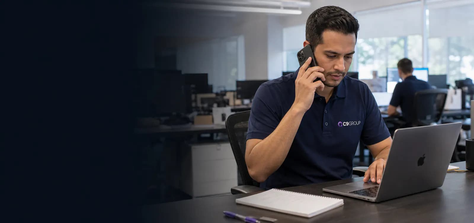 C9 GROUP staff member using a mobile phone and laptop in a real office environment